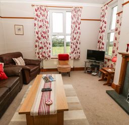 A living room with leather sofas a coffee table a television and a fireplace at Dinas Farmhouse Annex in Caernarfon
