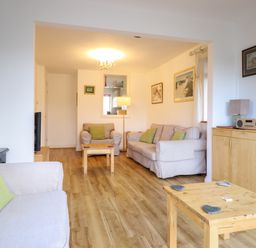 A living room with beige sofas green cushions wooden tables and a wooden cabinet at Dehangfa in Fairbourne