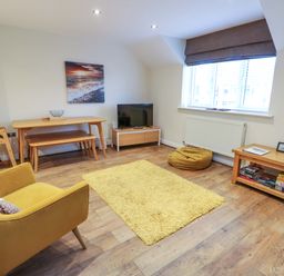 A living room with a table and a television at Y Enciliad Rhosneigr