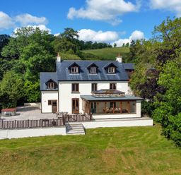 A three story house with a patio and garden surrounded by trees at Oakwood House in Rhayader