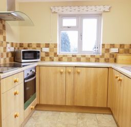 A kitchen with a microwave oven stovetop sink knives and wooden cabinets at Broadway Lands Farm in Little Dewchurch