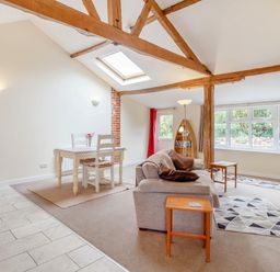 A living room with a sofa table and chairs exposed wooden beams and a skylight at The Hen House in Diss near Gissing