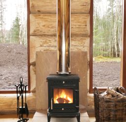 A wood burning stove with fire inside between two tall windows in a log cabin at Moorhen Lodge in North Kessock