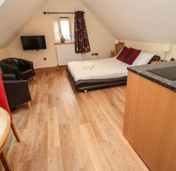 A bedroom with a bed two chairs a wall mounted tv and a countertop at St  Cruz in Embleton