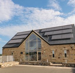 A stone building with a large glass entrance and solar panels on the roof at Mill View in Embleton