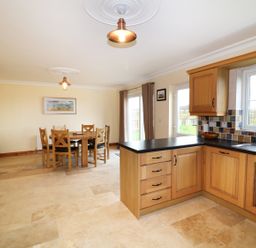 A kitchen and dining area with wooden cabinets dining table and chairs at Benbulben View in Tullaghan County Leitrim