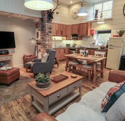 An open plan living room and kitchen with wooden furniture and a wall mounted television at The Olde Stables in Warkworth