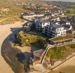 An aerial view of buildings by the beach with a sandy area and dunes at Chapel Rock View The Dunes in Perranporth
