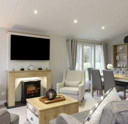 A living room with a fireplace armchair dining table and chairs at Woodstock Lodge in Wemyss Bay
