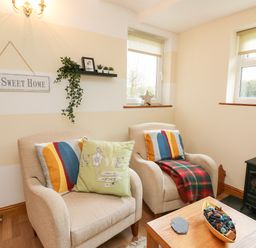 A sitting area with two armchairs a small table and a fireplace at Blaenywawr Annexe in Lampeter