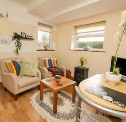 A sitting area with two armchairs a small wooden table and a dining table with chairs at Blaenywawr Annexe in Lampeter