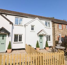 A row of cottages with green doors and a wooden fence in front at Martin Cottage in Ilfracombe