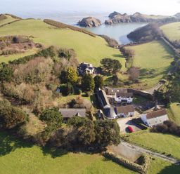 An aerial view of buildings surrounded by grassy fields trees and a body of water at Kingfisher Cottage in Ilfracombe