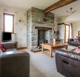 A living room with leather sofas a wooden coffee table and a stone fireplace at Blaen Henllan in Builth Wells