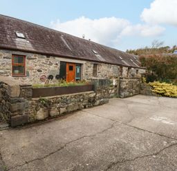 A stone building with windows and a garden area at Beudy Mawr Y Felinheli