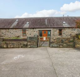 An outdoor view of a stone building with a gate at Beudy Mawr Y Felinheli