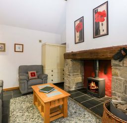 A living room with a fireplace and seating area at Beudy Mawr Y Felinheli