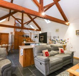 A living room with a sofa and kitchen island at Beudy Mawr Y Felinheli