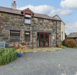 An outdoor view of a stone building with a bench at Hafod in Y Felinheli