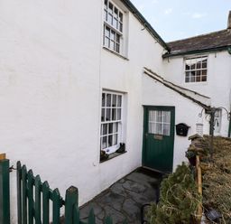 An outdoor entrance area with a green door and windows on a white building at Castle Lodge in Borrowdale