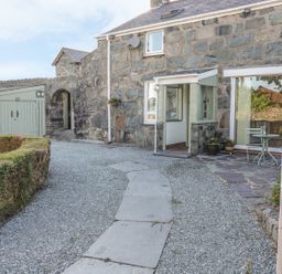Stone house with gravel pathway and small patio table and chairs at Y Cilgwyn in Trawsfynydd