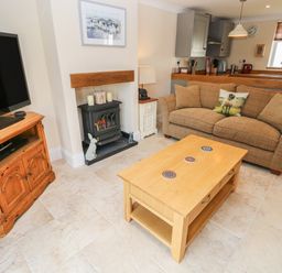 A living room with a sofa and coffee table near a fireplace and television at Pottery Cottage in Begelly near Kilgetty