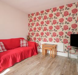 A living room with a red sofa and coffee table at The Farmhouse in Brynsiencyn near Newborough