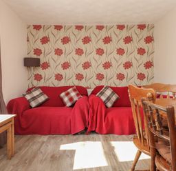 A living room with a sofa and dining table at The Farmhouse in Brynsiencyn near Newborough