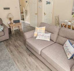 A living room with two sofas a small table with a lamp and a dining table with chairs at Sandy Bay House in Saundersfoot