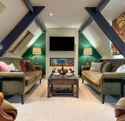 A sitting room with two sofas a coffee table with wine glasses a television and lamps at Geltsdale East Wing in Wetheral