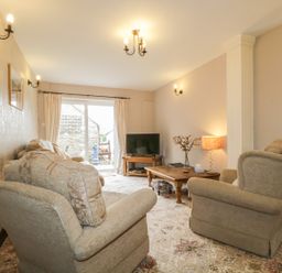 A living room with armchairs a wooden coffee table and a television at Springarth Cottage in Newby
