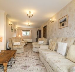 A living room with armchairs a sofa a wooden coffee table and floral carpet at Springarth Cottage in Newby