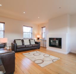 A living room with two brown leather sofas a patterned rug a wall-mounted fireplace and a television on a wooden stand at Wrenville in Keswick