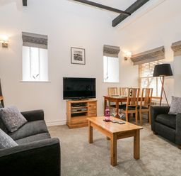 A living room with sofas coffee table television dining table and chairs at The Old Hayloft in Keswick