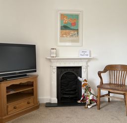 A living room with a television, chair, and fireplace at Prospect Lodge in Portinscale