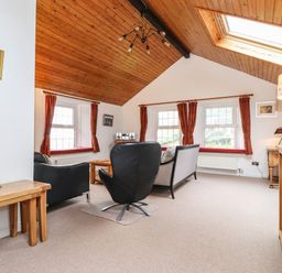 A living room with armchairs sofa coffee table and wooden ceiling at Coombe Cottage in Borrowdale