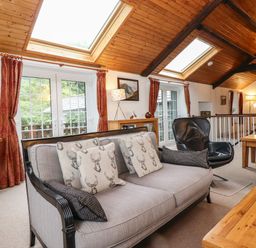 A living room with sofas chairs wooden tables and skylights at Coombe Cottage in Borrowdale