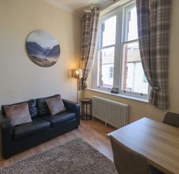 A living room with a sofa and dining table at St Johns View in Keswick
