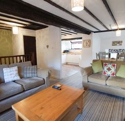 A living room with two sofas a wooden coffee table and an open kitchen at Laurel Cottage in Spark Bridge