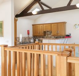A kitchen area with wooden cabinets and a wooden railing in the foreground at Skiddaw in Cockermouth