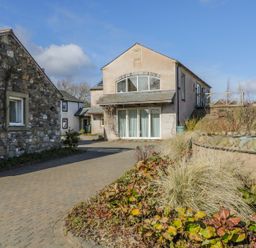 A paved driveway between two houses with a garden bed in the foreground at Skiddaw in Cockermouth