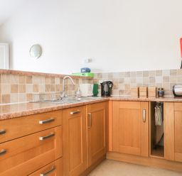 A kitchen with wooden cabinets a sink a kettle a toaster and canisters at Esthers Barn in Cockermouth
