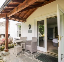 An outdoor patio with a wooden roof and two wicker chairs with a table outside a room at Thirlmere Suite in Thirlmere