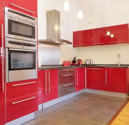 A kitchen with red cabinets stainless steel oven and appliances at Keswick Loft in Keswick