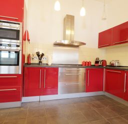 A kitchen with red cabinets stainless steel appliances and cooking utensils at Keswick Loft in Keswick