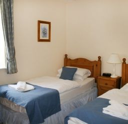 A bedroom with two single beds beside each other with blue bed runners and white bedskirts at Whitbarrow Holiday Village Troutbeck 5 Ullswater