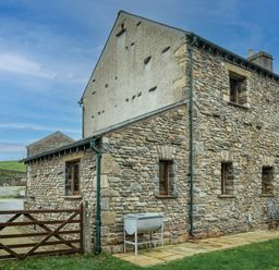 Stone house with multiple windows wooden gate and outdoor furniture at Grayrigg Foot Stable in Grayrigg