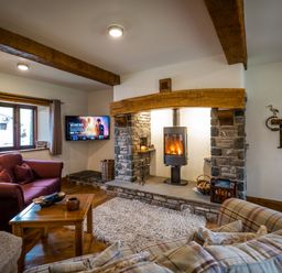 A living room with a wood burning stove in a stone fireplace a wooden coffee table and two sofas at Grayrigg Foot Stable in Grayrigg