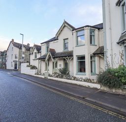 A street view of white painted houses with green window frames and small front gardens at Greta Mill in Keswick