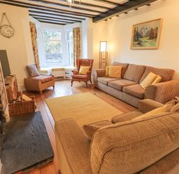 A living room with sofas armchairs a fireplace and a bay window at Greta Mill in Keswick